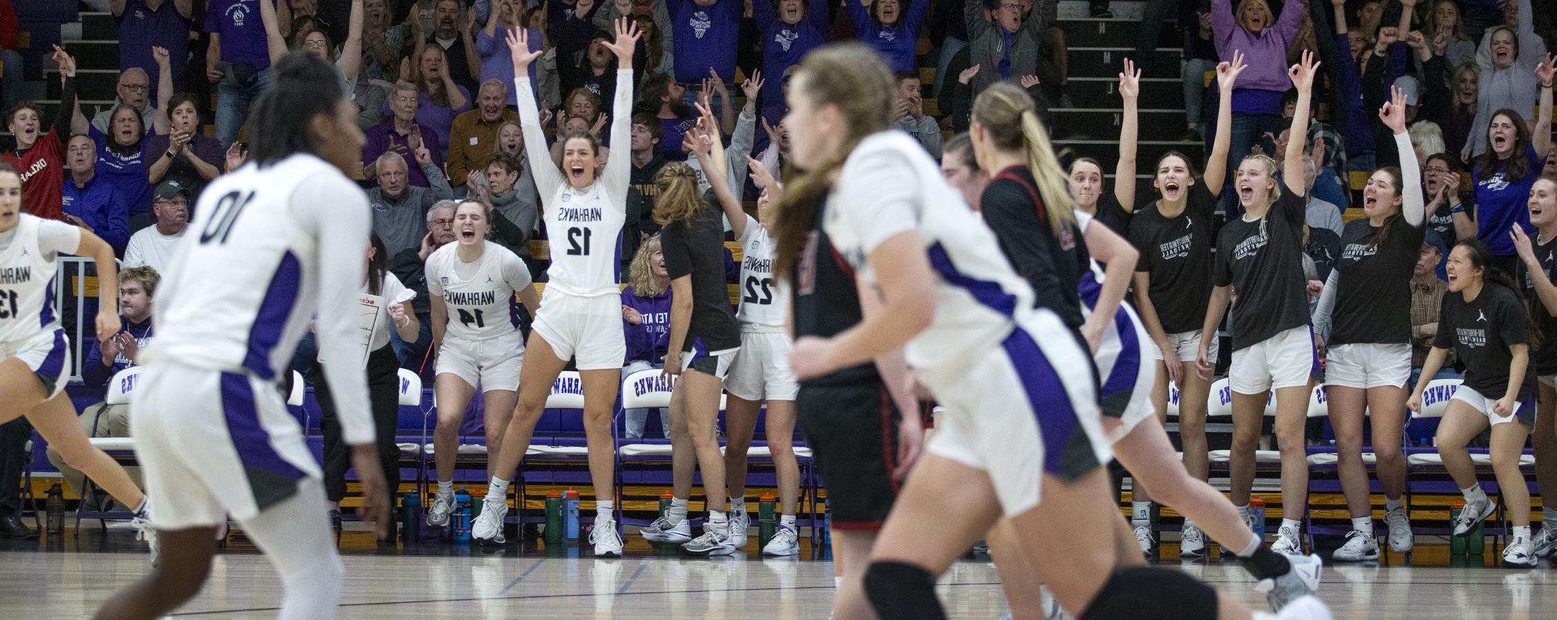 The women's basketball team jumps and cheers during a game.